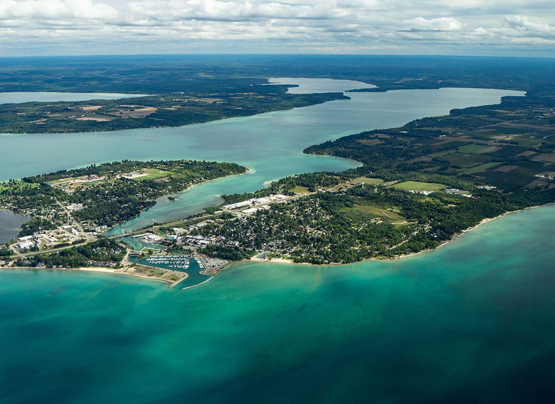 Elk Rapids, MI - Aerial View of Land Surrounded by a Deep Blue Lake in Elk Rapids Michigan on a Sunny Day